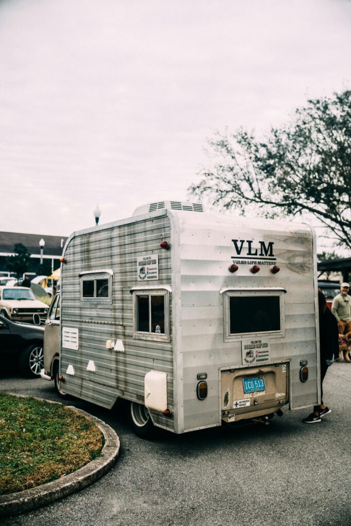 Vintage caravan parked outdoors with trees in background, evoking a sense of travel and adventure.